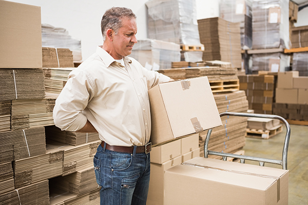 man with back pain lifting boxes in the workplace