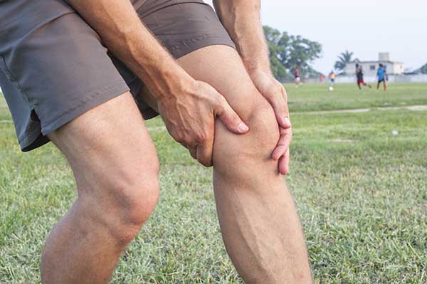 Person in Grass Grabs Knee Person in Grass Grabs Knee