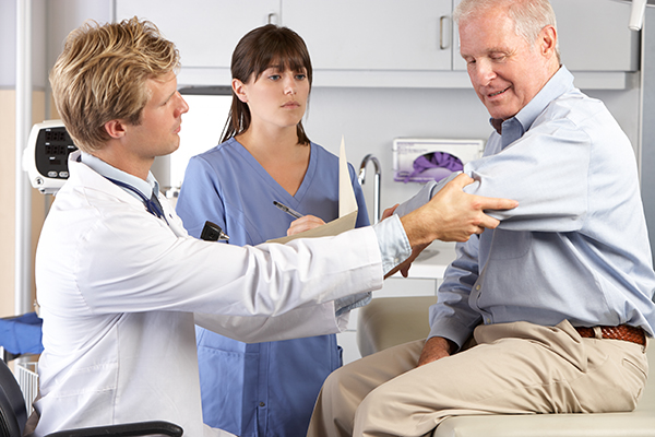 Elbow doctor and technician examine patient for elbow pain